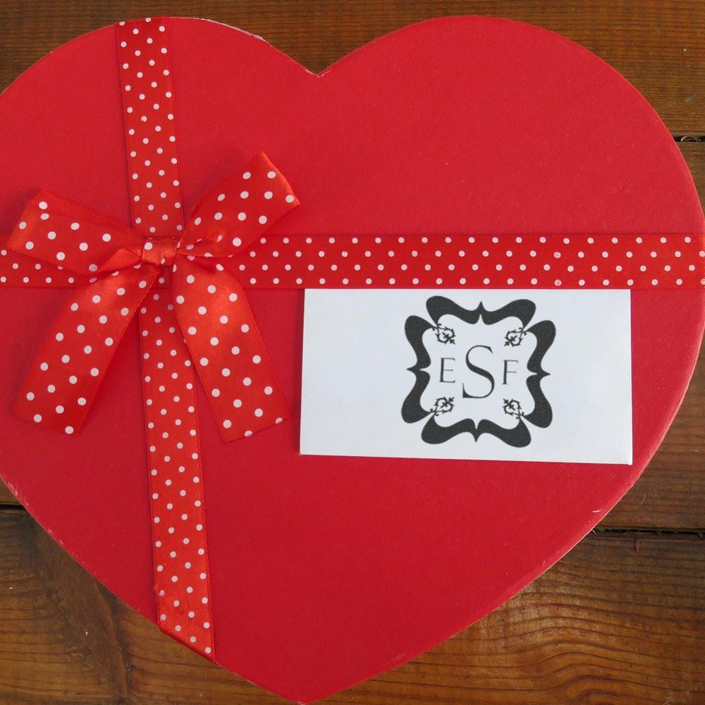 Heart-shaped red gift box with custom monogram rubber stamp card and polka dot ribbon for personalized packaging.