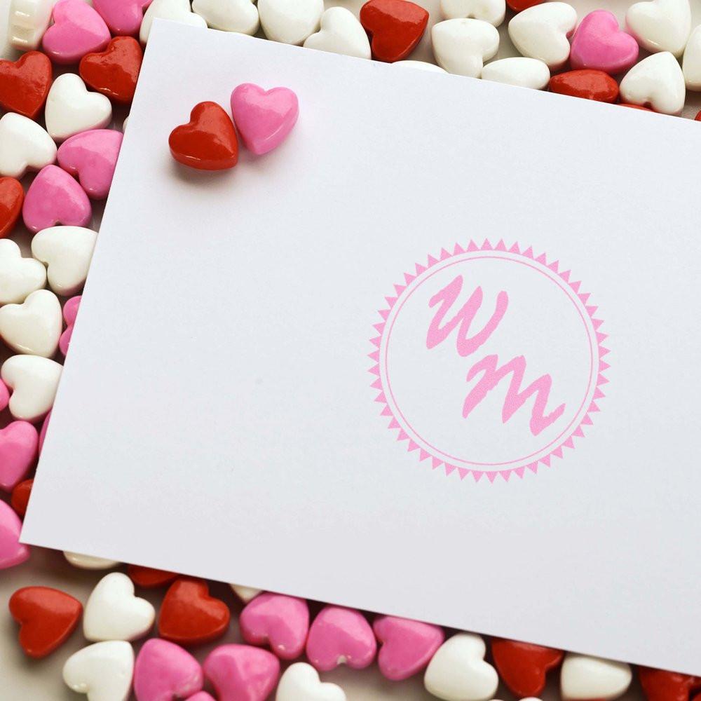 Custom pink wedding monogram rubber stamp on blank card with heart candies for personalized stationery and favors.
