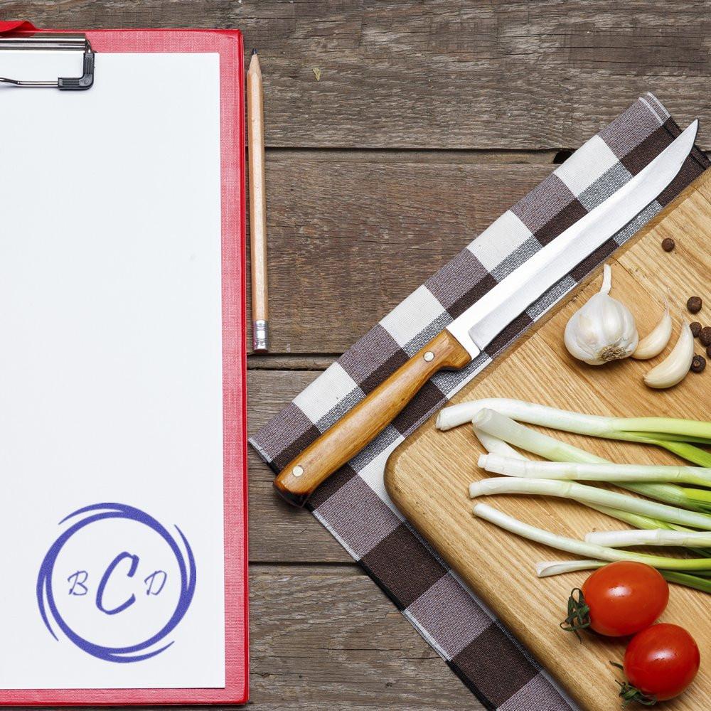 Custom monogram rubber stamp with BCD logo on clipboard, ideal for personalized kitchen branding and chef packaging.