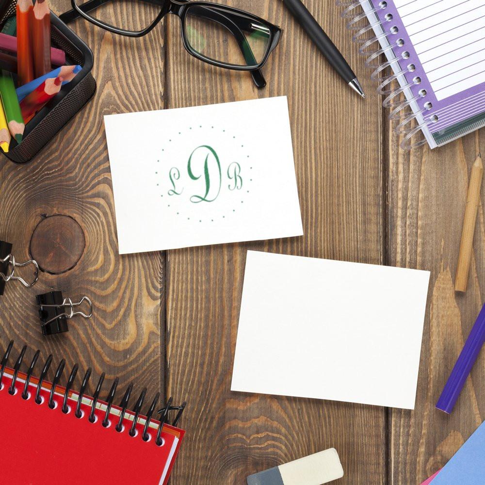 Top view of a DIY stationery desk with monogram LDB note cards, pens, glasses, and notebooks for custom branding.