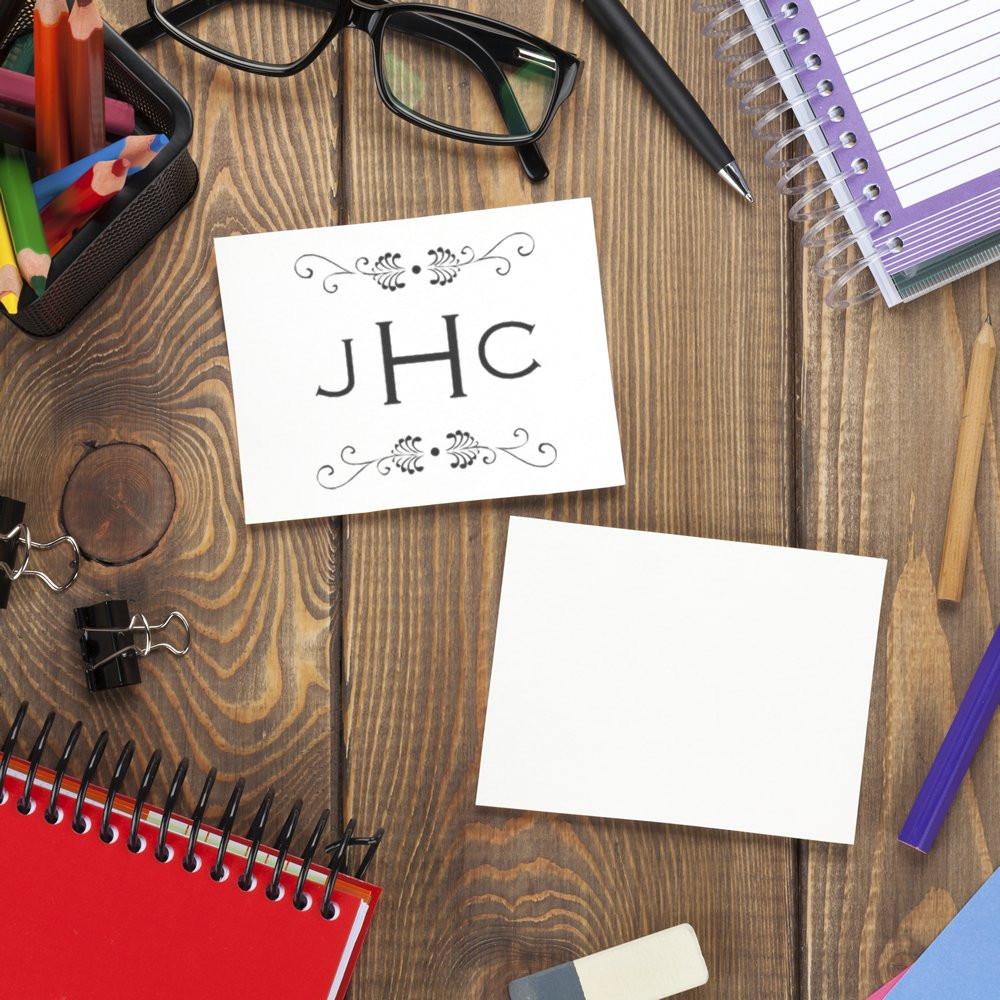 Custom monogram rubber stamp sample on blank card, styled with stationery and desk accessories for branding.