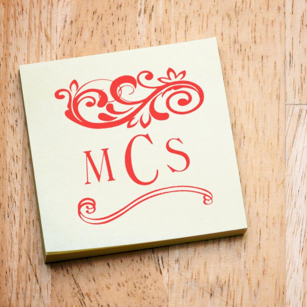 Red floral monogram MC's on a greeting card placed on rustic wooden background, decorative custom typography and design.