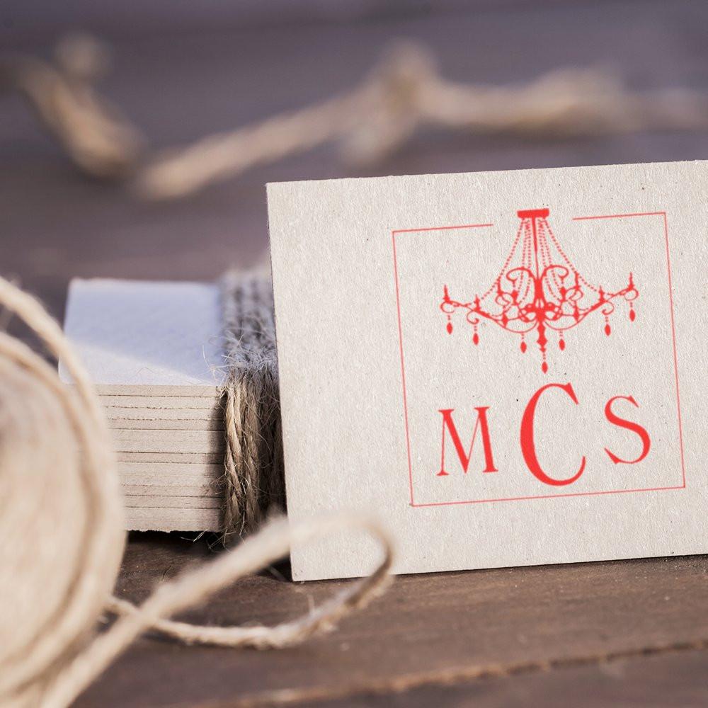 Rustic gift tag with red chandelier logo and MCS text, tied with twine on wooden surfacebrand label for decor.