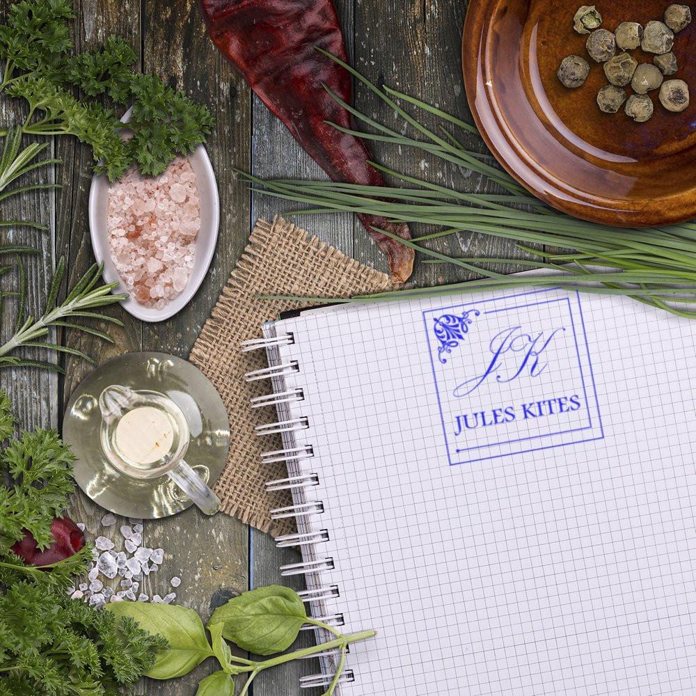 Custom rubber stamp imprint on a graph notebook page, featuring the Jules Kites logo for personalized stationery branding.