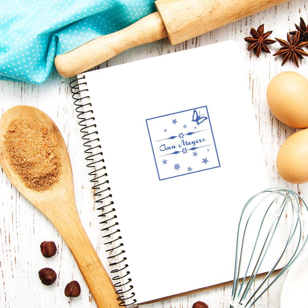 Custom rubber stamp imprint on recipe notebook with baking tools, perfect for bakery branding