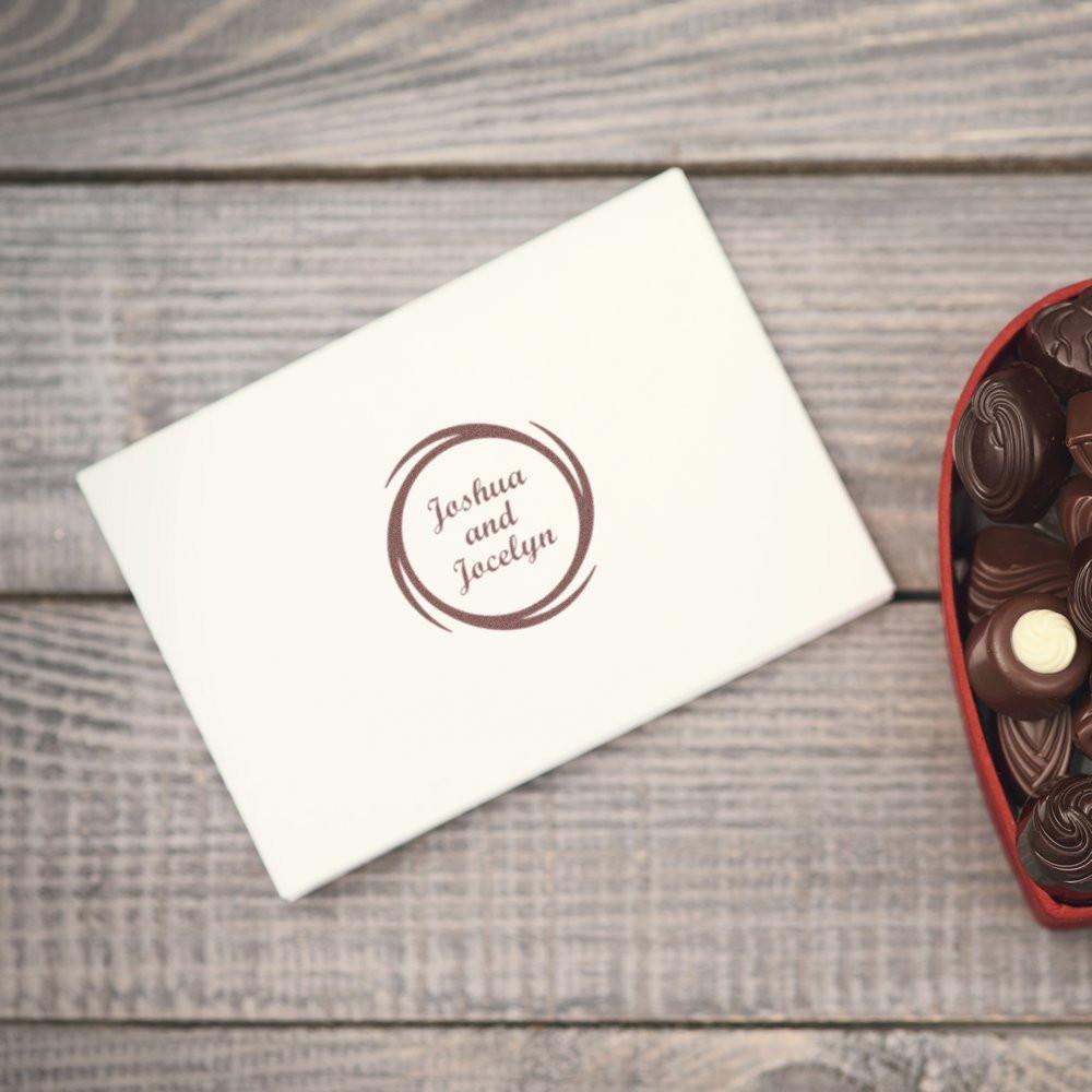 Custom wedding rubber stamp with Joshua and Jacelyn monogram on envelope, styled with chocolates on rustic wood.