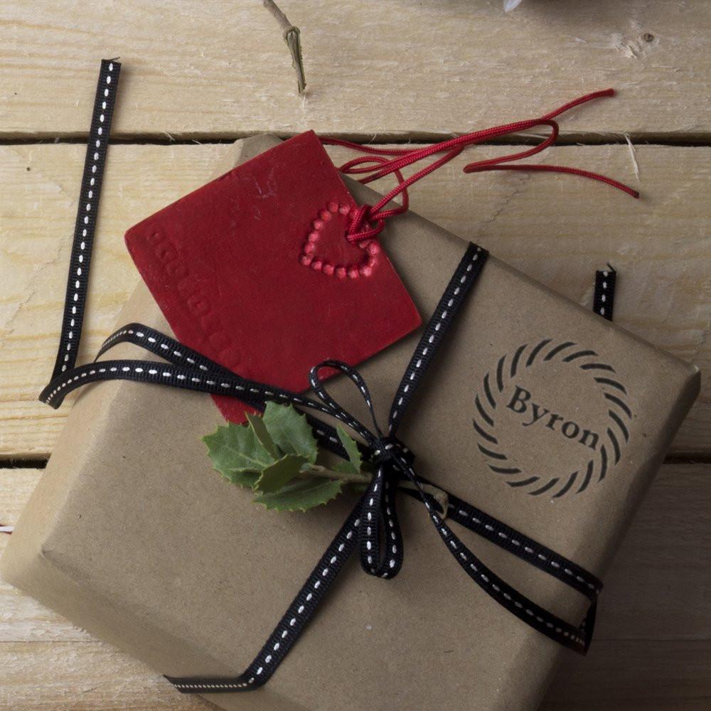 Custom rubber stamp on kraft gift wrap with ribbon and heart tag, showcasing personalized packaging for handmade gifts.