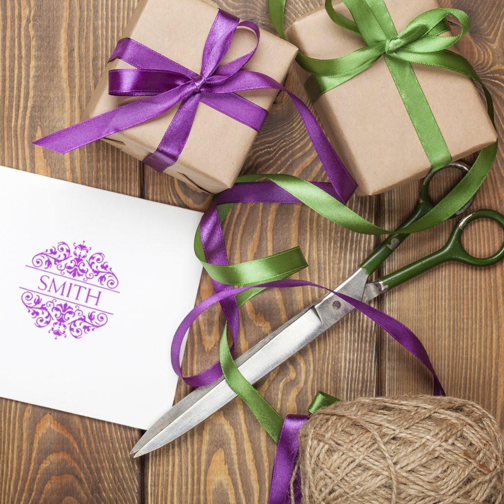 Custom rubber stamp impression on gift wrap with ribbon, twine, and wrapped presents for personalized packaging.