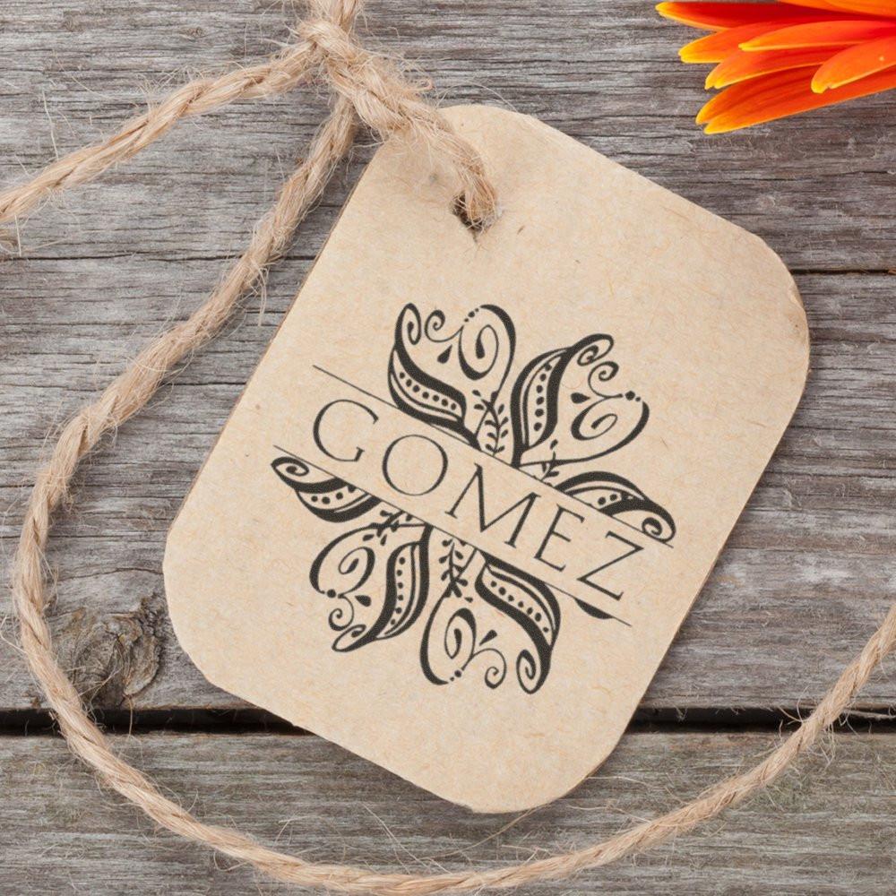 Decorative kraft paper gift tag with LOVE typography, tied with twine on rustic wooden background with flower accents