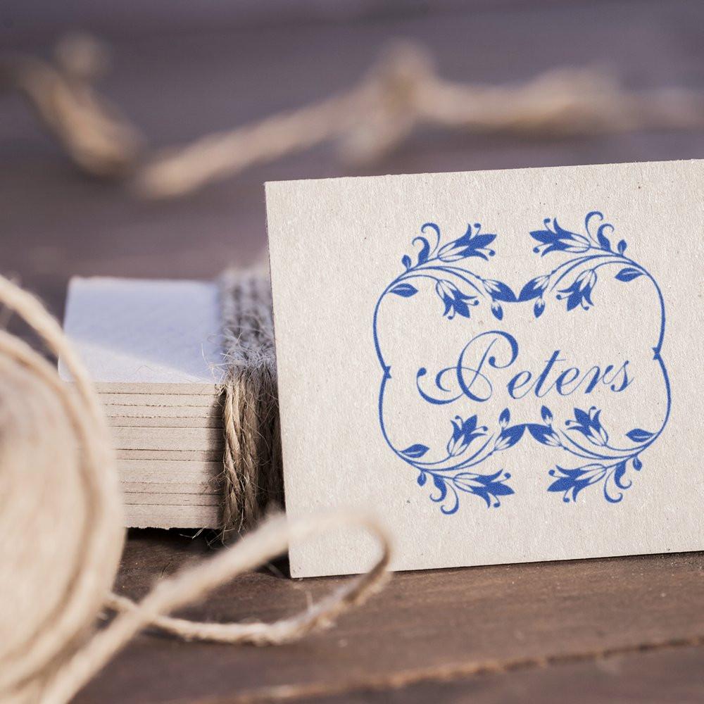 Custom floral rubber stamp with blue Peters imprint on cardstock for personalized stationery, wedding favors, and branding.