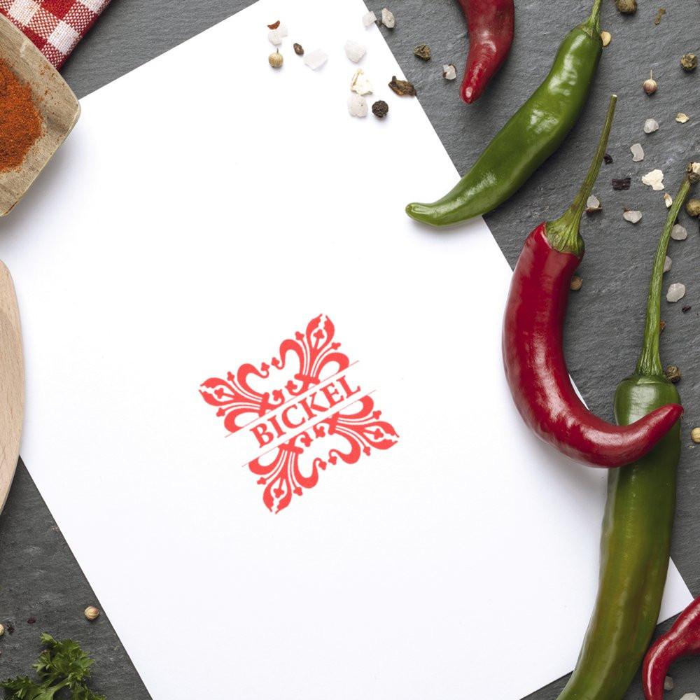 Custom rubber stamp impression with BICKEL logo on paper, styled with chili peppers and spices.