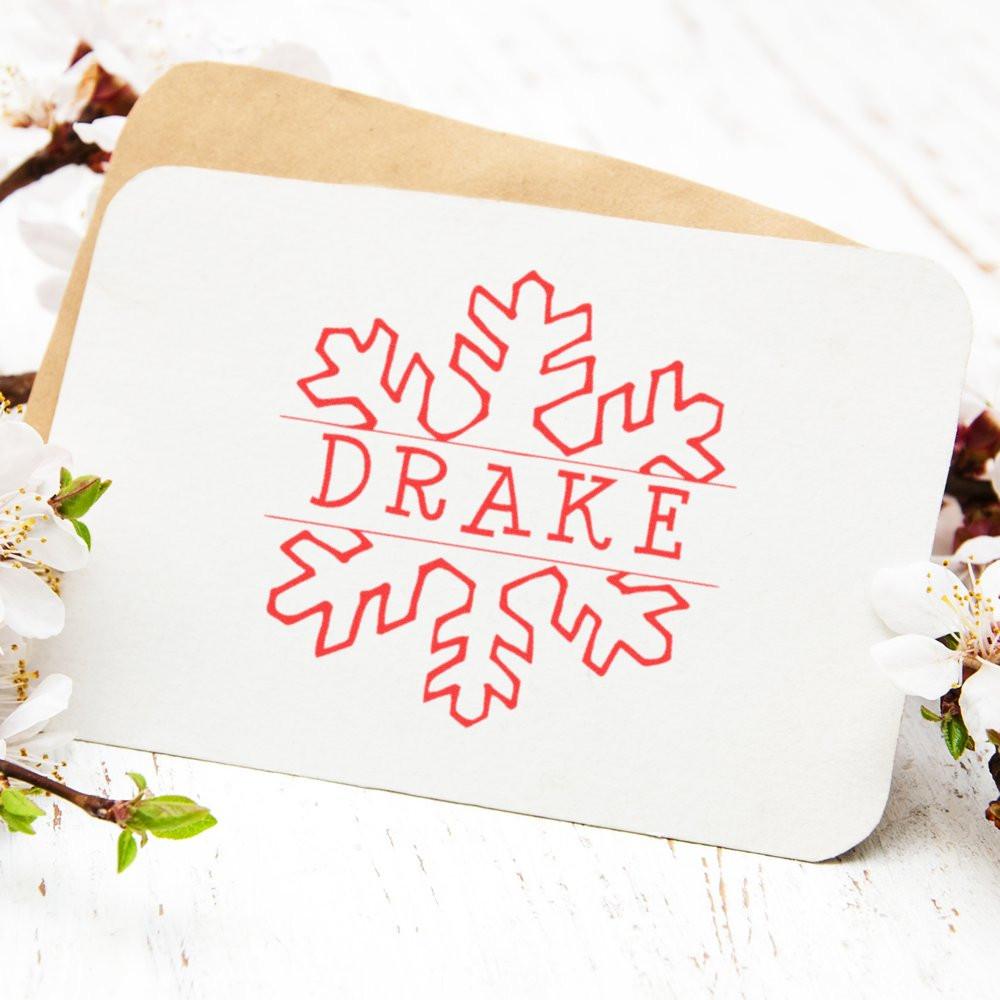 Snowflake-themed Drake logo on a bakery-style food box, showcasing seasonal dessert packaging on a rustic white table.