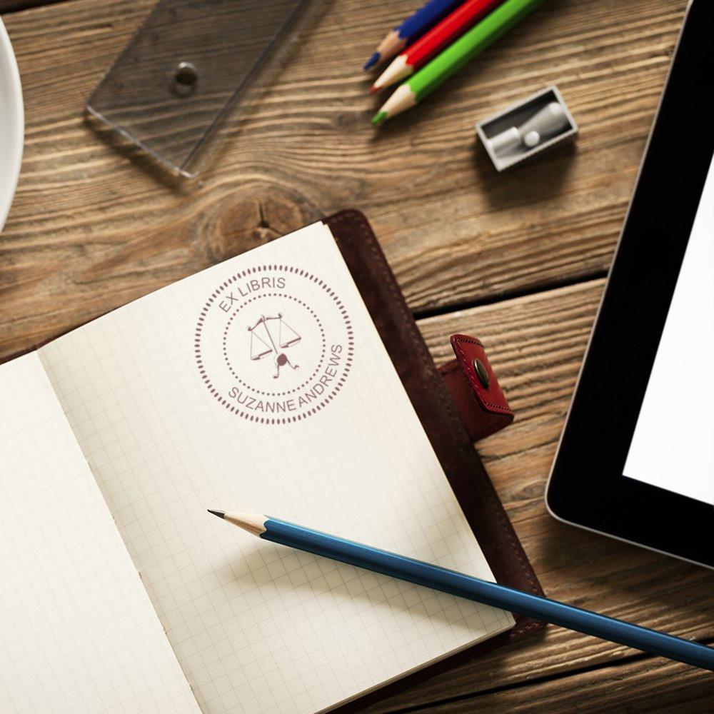 Custom ex libris rubber stamp on notebook for personalized book ownership and stationery branding.