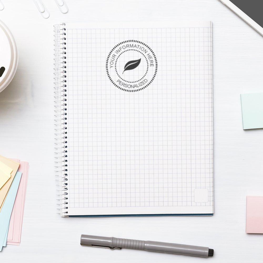 Personalized rubber stamp impression on a grid notebook, featuring a custom logo design for branding and stationery.
