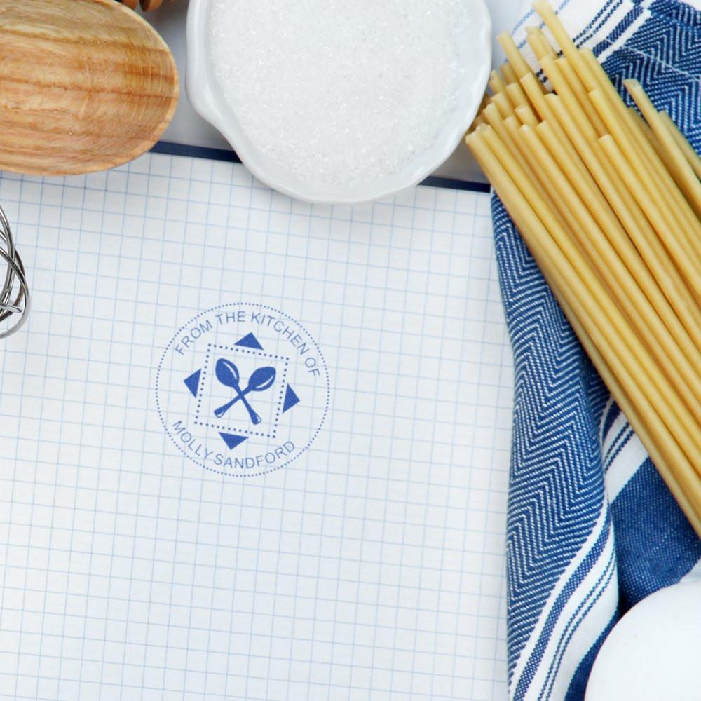 Custom kitchen rubber stamp with blue ink impression reading From the Kitchen of Molly Sandford for homemade recipes.