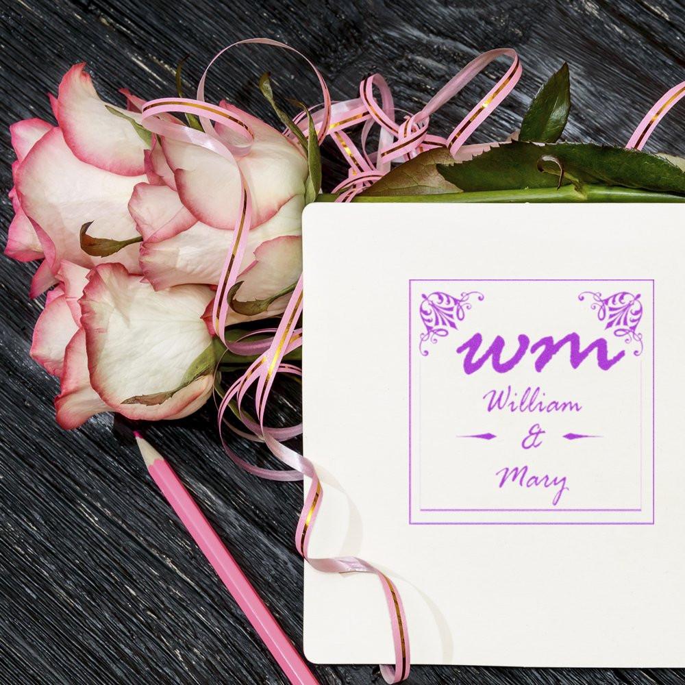 Personalized wedding rubber stamp with WM monogram and William & Mary design, styled with pink roses and ribbon.