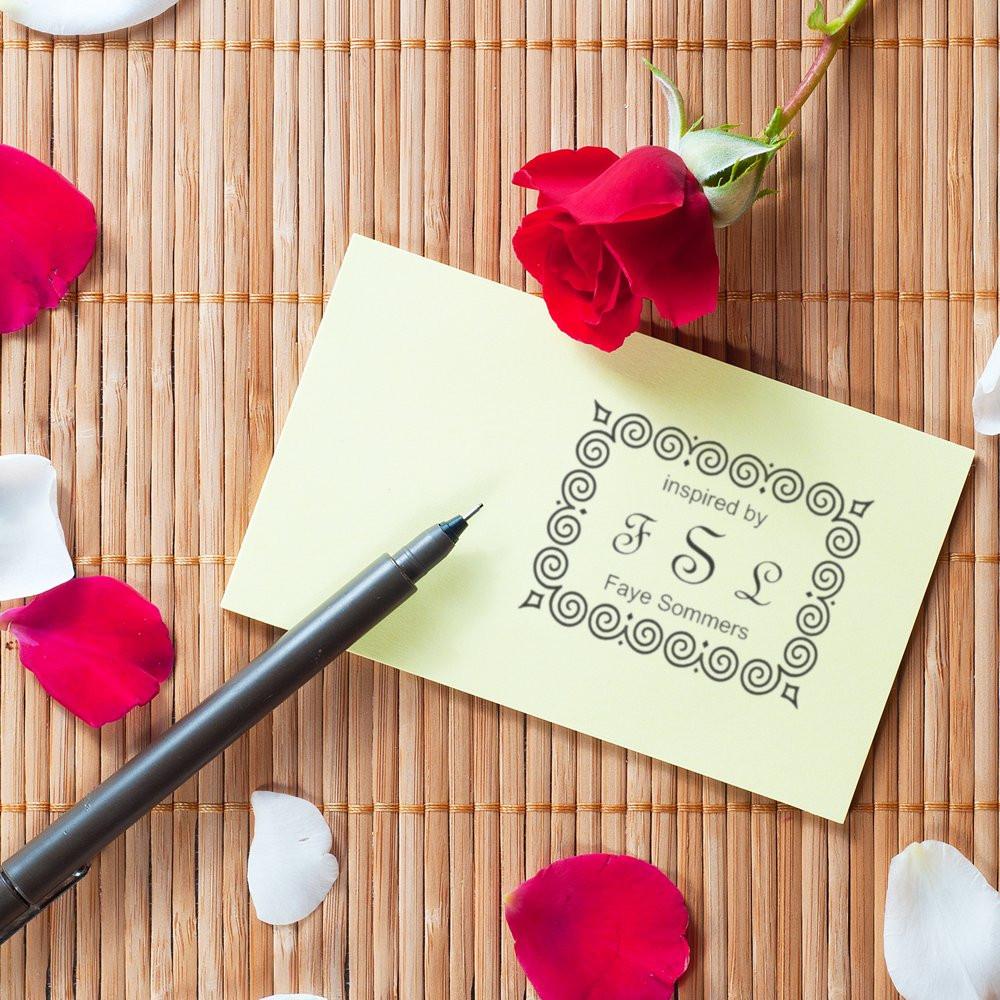 Custom rubber stamp sample on note card with pen and rose petals, featuring an ornate Inspired by FSL Faye Sommers design.