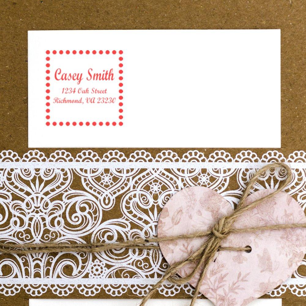 Personalized return address rubber stamp on a wedding envelope with decorative lace and heart tag.