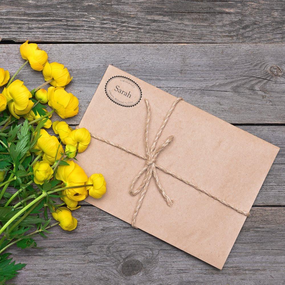 Custom oval rubber return address stamp on kraft paper package tied with twine, ideal for personalized wedding gifts and packaging.