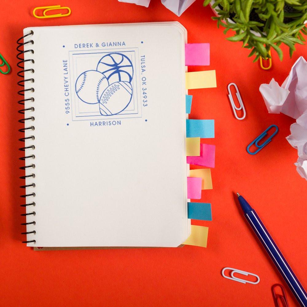 Personalized sports return address rubber stamp with baseball, basketball and football design on a notebook.