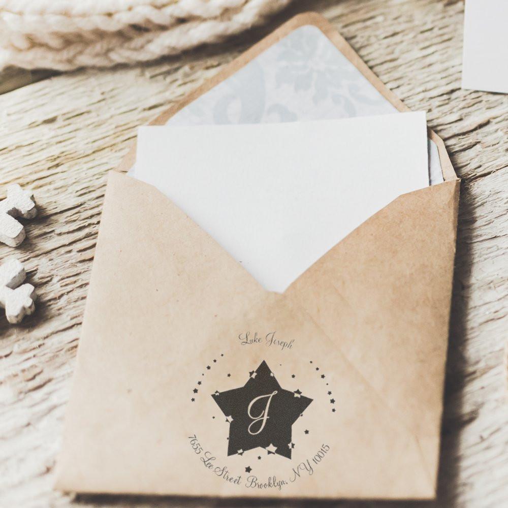 Personalized letterpress wedding invitation envelope with monogram on rustic wooden background, ready for mailing.