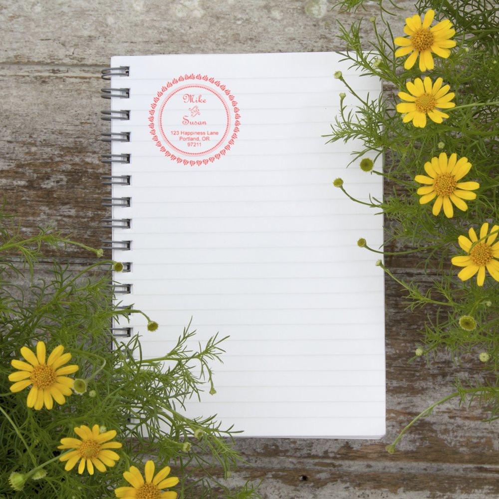 Custom return address rubber stamp impression on a notebook page, styled with yellow flowers for a personalized stationery look.
