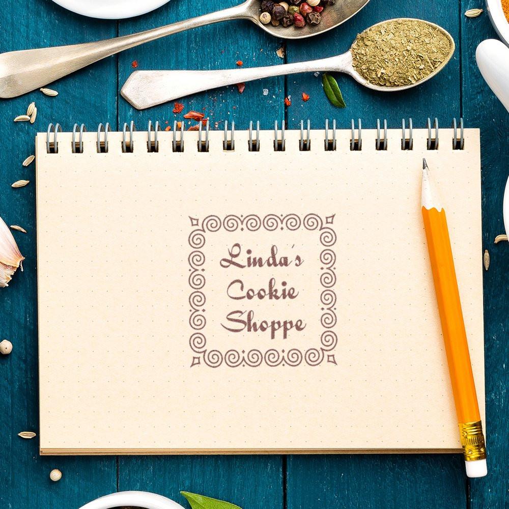 Custom rubber stamp for Lindas Cookie Shoppe logo on a notebook page, ideal for bakery branding and packaging.