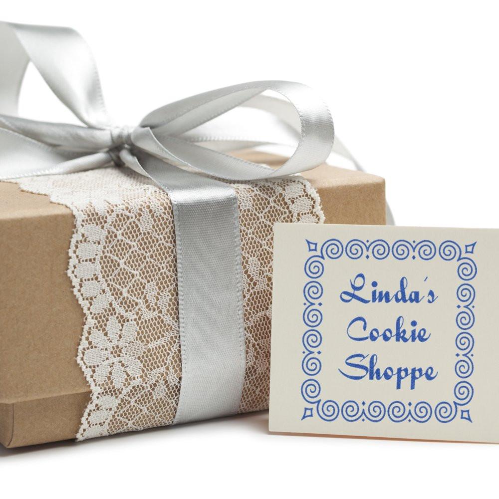Custom rubber stamp for Lindas Cookie Shoppe on a wrapped gift box with ribbon and lace packaging.