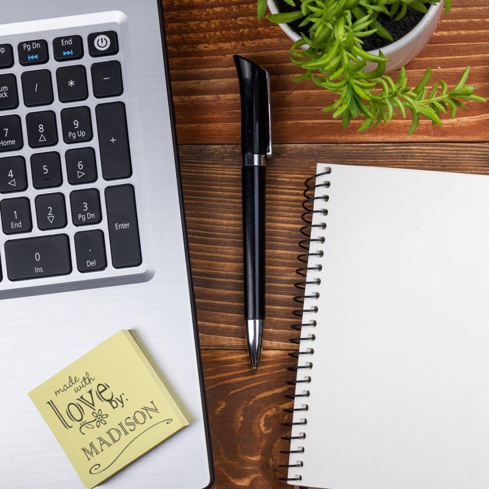 Personalized rubber stamp for handmade branding on a desk with laptop, pen, notebook, and plant.