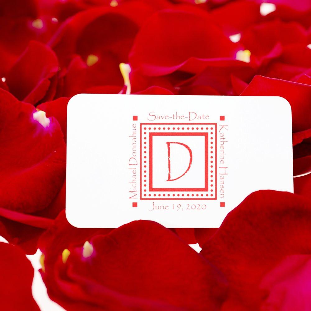 Custom wedding save-the-date rubber stamp with monogram initial on card, surrounded by red rose petals