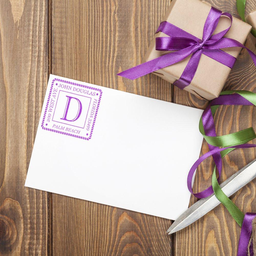 Personalized rubber stamp monogram on envelope with ribbon-wrapped gift for custom stationery and packaging.