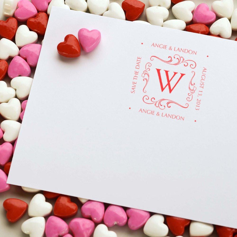 Custom wedding rubber stamp on save-the-date card with monogram W and Angie & Landon, framed by pink and white heart candies.