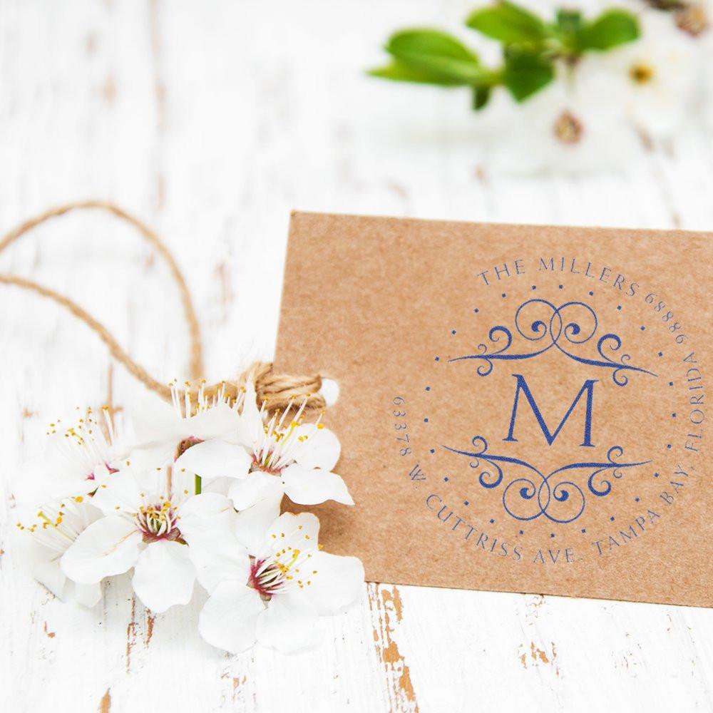 Custom return address rubber stamp with monogram M on kraft card, styled with white flowers for rustic wedding branding.