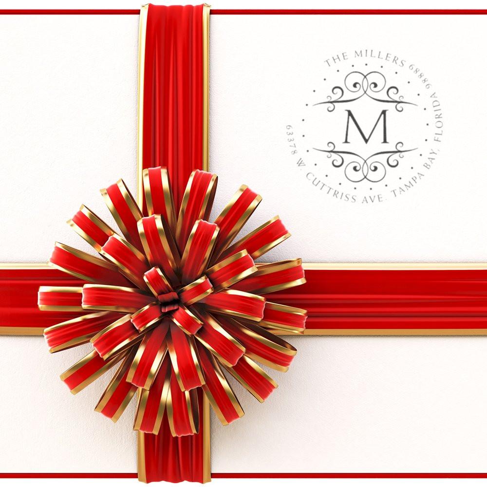 Custom monogram address rubber stamp for wedding invitations and gift wrapping with red and gold ribbon.