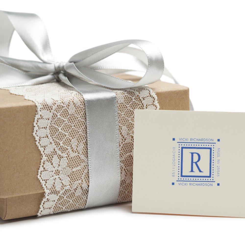 Custom monogram rubber stamp on a wrapped gift with ribbon and lace, ideal for personalized wedding stationery and packaging.