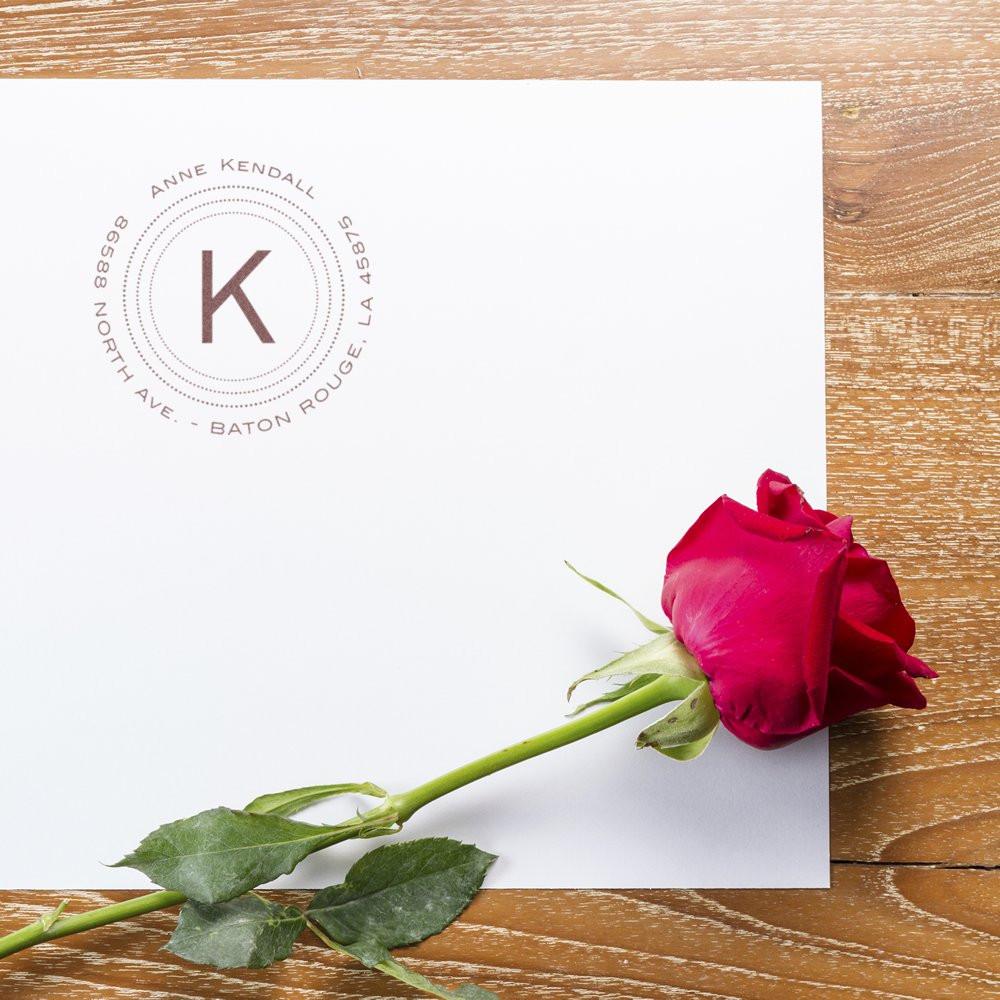Custom monogram return address rubber stamp on white envelope, ideal for wedding invitations, stationery, and branding.