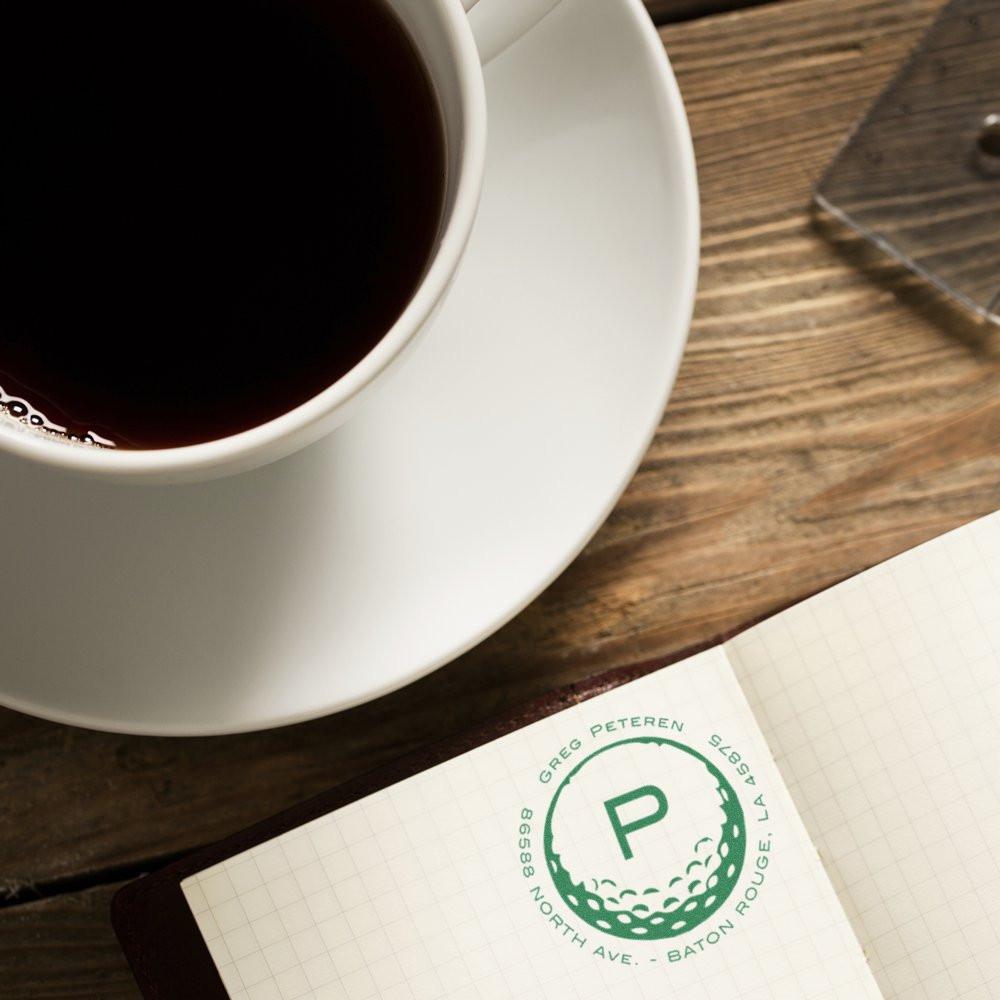 Personalized rubber stamp logo on notebook beside coffee cup, highlighting a custom business stamp design.