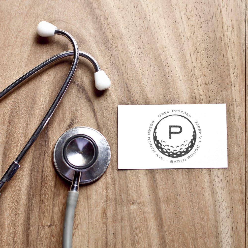 Custom rubber stamp logo imprint on a business card beside a stethoscope for medical office branding.