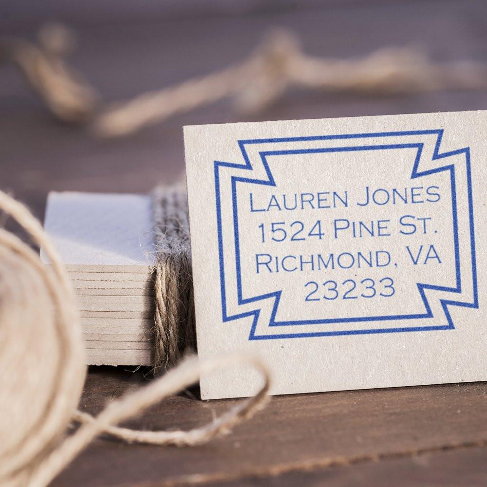 Custom address rubber stamp with blue geometric border showing Lauren Jones, 1524 Pine St., Richmond, VA 23233 on cream cardstock.