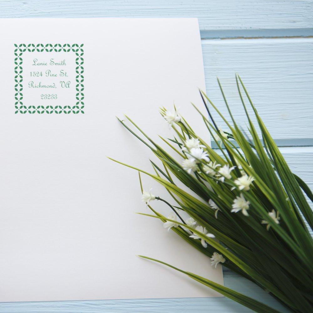 Custom return address rubber stamp on white envelope with decorative green border, ideal for personalized mailing and stationery.
