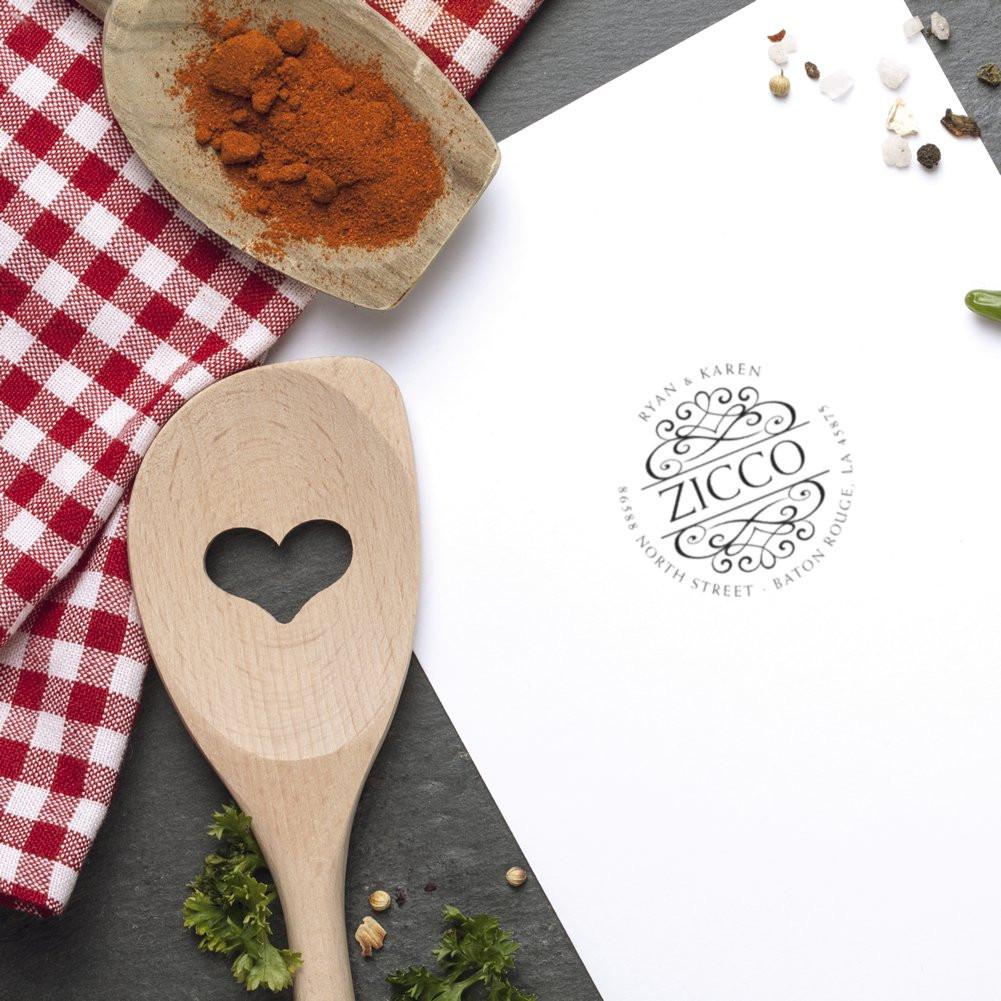 Custom rubber stamp logo impression on paper with wooden spoon and spices, for kitchen branding and recipe packaging.