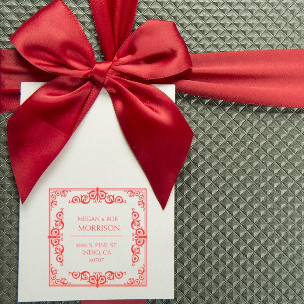 Custom wedding return address rubber stamp on gift tag with red bow and ornate monogram border design.