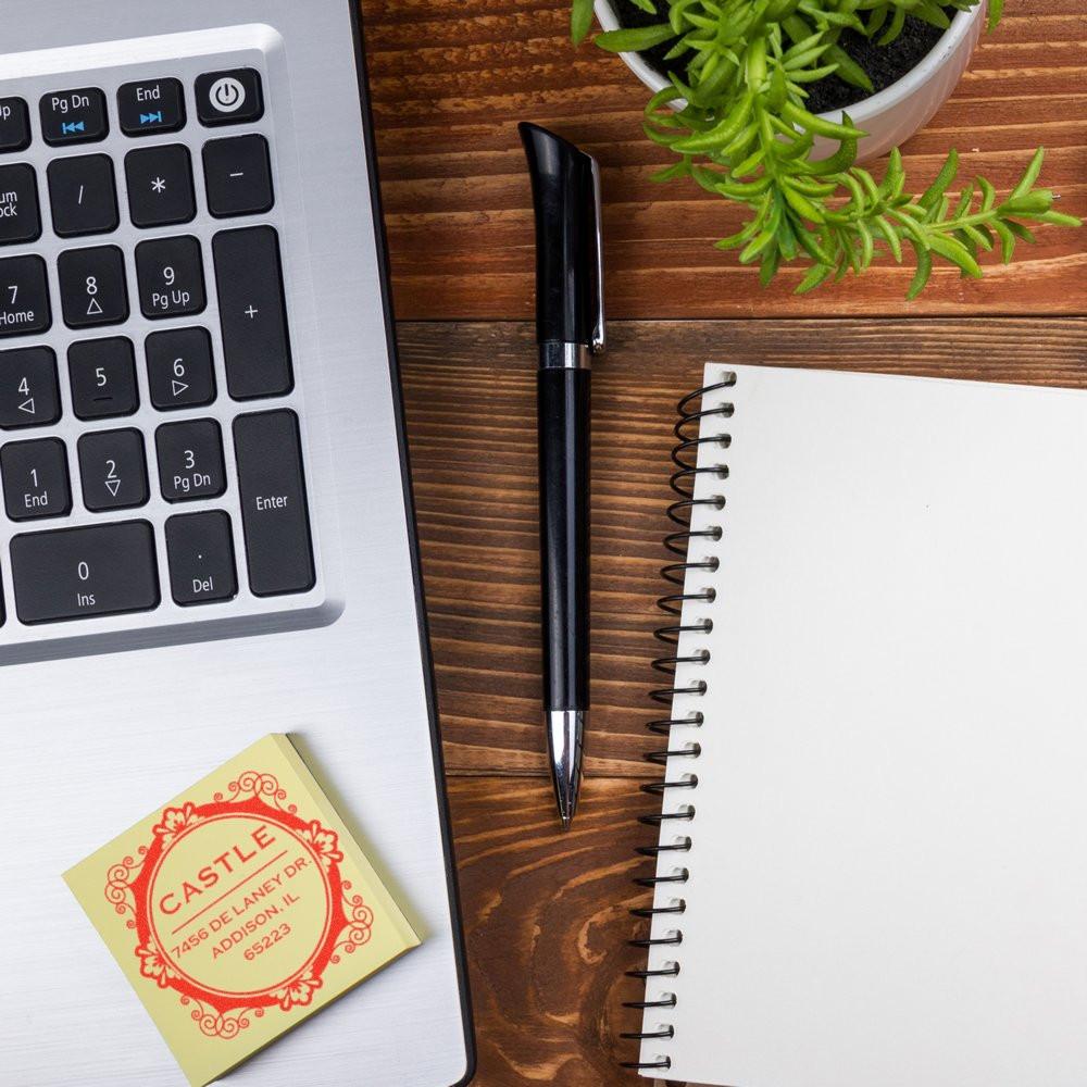 Custom rubber return address stamp on a desk with laptop, pen and notebook for business mailing.