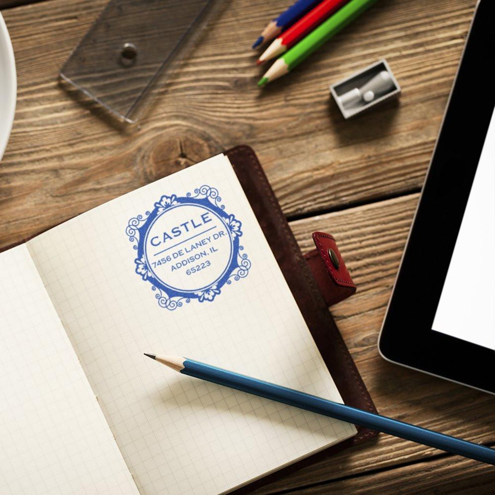Custom rubber address stamp on notebook at desk, showing personalized business stationery and branding for home office use.