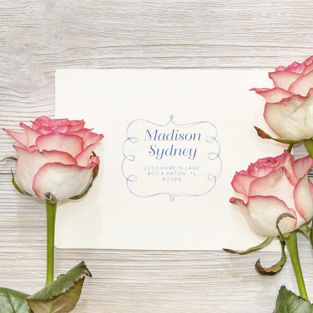 Personalized name card for Madison Sydney with blue address and pink roses on white wood background