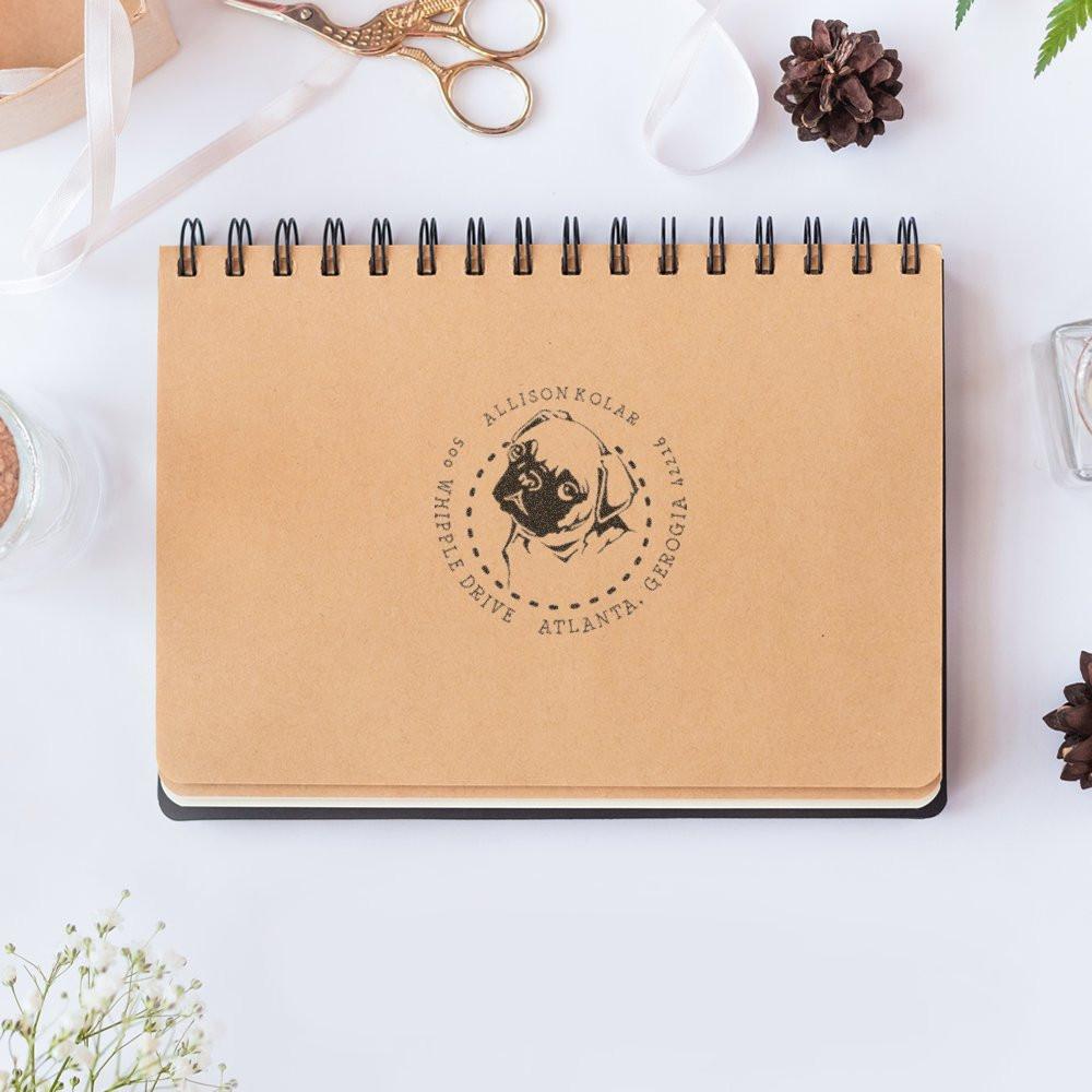 Custom return address rubber stamp with dog logo on kraft notebook, personalized for Allison Kolar in Atlanta, Georgia.
