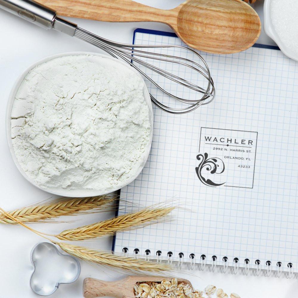 Return address rubber stamp imprint on a notebook with baking tools, flour, and wheat decor.