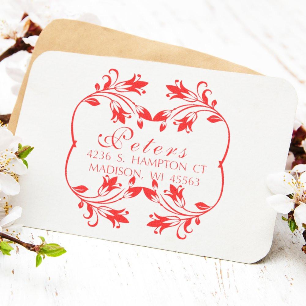 Custom floral return address rubber stamp for wedding invitations, featuring red decorative monogram and family name.