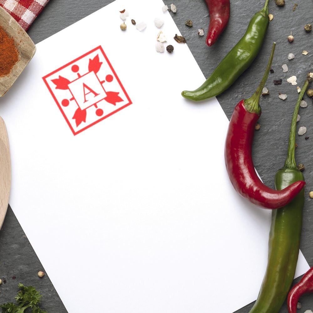 Red custom rubber stamp on blank paper with chili peppers, ideal for personalized food packaging branding.