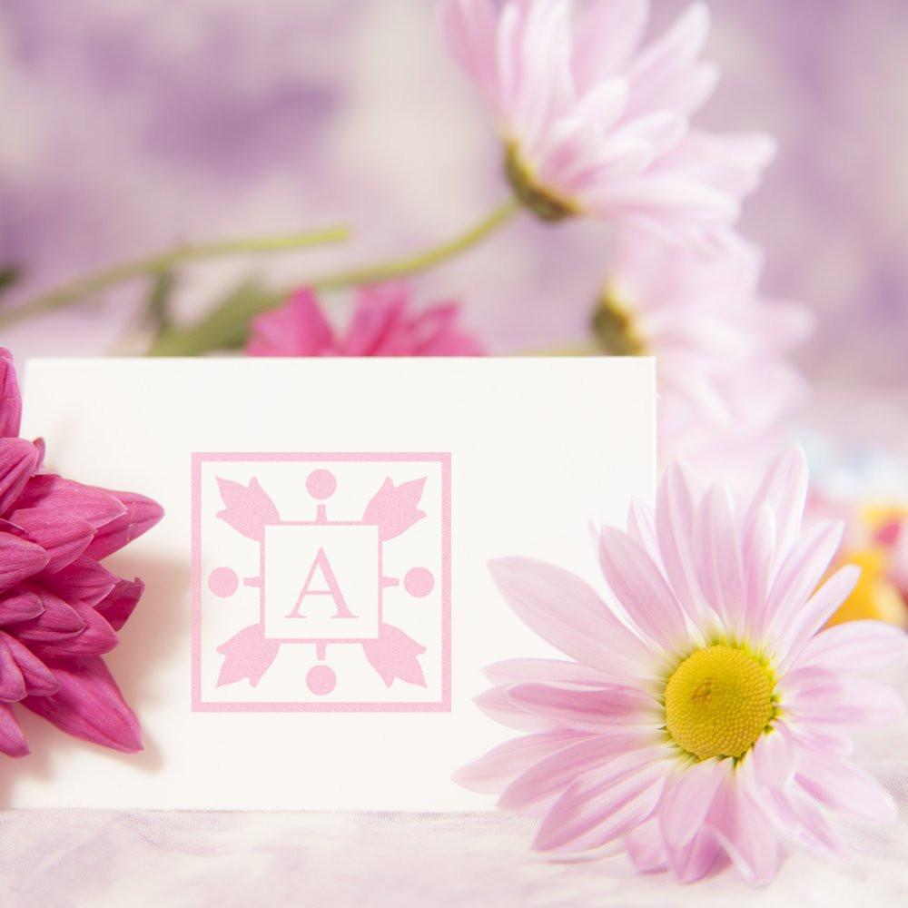 Pink floral monogram rubber stamp on stationery, ideal for custom wedding invitations and elegant branding.